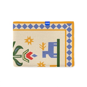 Pu&ograve; includere: Tessuto rettangolare piegato con sfondo crema e motivo geometrico blu, giallo, rosso e verde. Il design include motivi a stella e floreali. La parola "ORNER" &egrave; stampata su un'etichetta blu.