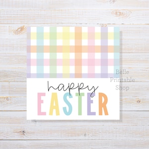May include: A square card with a pastel plaid pattern at the top and the words "happy EASTER" in colorful letters below. The card is on a white wooden surface. The text "Belle Printable Shop" is in the upper right corner.