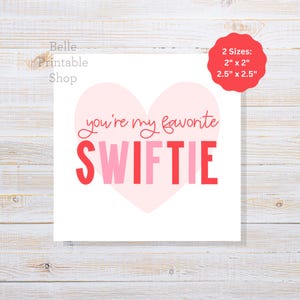 Puede incluir: Tarjeta de San Valentín imprimible con un corazón rosa y el texto "you're my favorite SWIFTIE" en letras rojas y rosas. La tarjeta está disponible en dos tamaños: 2 pulgadas por 2 pulgadas y 2,5 pulgadas por 2,5 pulgadas.