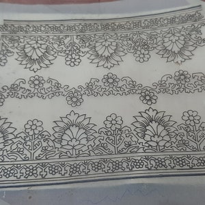 May include: A sheet of paper with three black and white floral designs printed on it. The designs are intricate and detailed, featuring flowers, leaves, and vines.