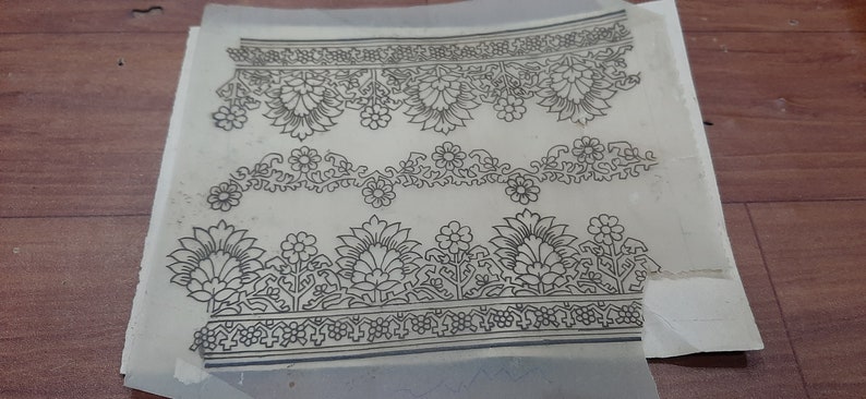 May include: A sheet of paper with three black and white floral designs printed on it. The designs are intricate and detailed, featuring flowers, leaves, and vines.