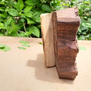 Puede incluir: Primer plano de un bloque de madera con un borde decorativo festoneado. El bloque est&aacute; hecho de madera marr&oacute;n oscura y tiene una tira de madera marr&oacute;n m&aacute;s clara unida a un lado.