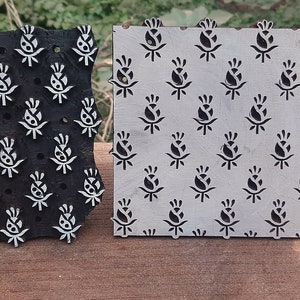 Op de afbeelding: Twee houten drukblokken met een bloemenmotief. De blokken zijn zwart en wit en hebben een reli&euml;fmotief. De blokken worden gebruikt voor het bedrukken van stoffen.