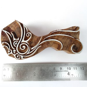 K&ouml;nnte beinhalten: Ein Holzblock-Stempel mit einem wei&szlig;en floralen Design. Der Stempel ist etwa 10 cm lang und wird neben einem Lineal gezeigt.