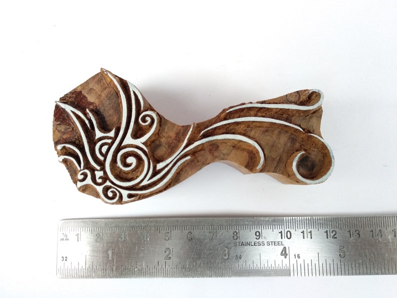 K&ouml;nnte beinhalten: Ein Holzblock-Stempel mit einem wei&szlig;en floralen Design. Der Stempel ist etwa 10 cm lang und wird neben einem Lineal gezeigt.