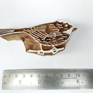 K&ouml;nnte beinhalten: Ein Holzblock-Stempel, der mit einem detaillierten Design eines Vogels geschnitzt ist. Der Vogel ist mit wei&szlig;er Farbe umrandet und hat einen braunen Holzk&ouml;rper.