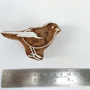 K&ouml;nnte beinhalten: Ein Holzblock-Stempel mit einer wei&szlig;en Umrandung eines Vogels. Der Stempel ist etwa 5 cm lang und 2,5 cm breit.