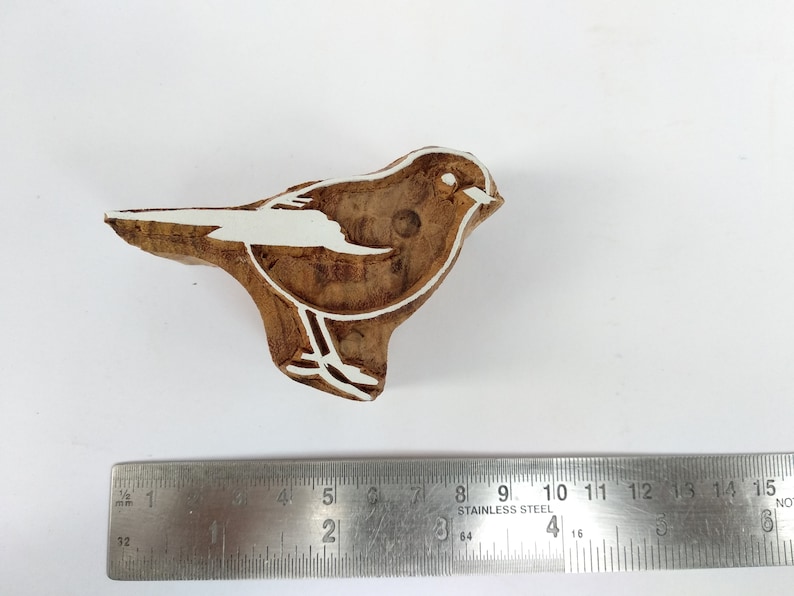 K&ouml;nnte beinhalten: Ein Holzblock-Stempel mit einer wei&szlig;en Umrandung eines Vogels. Der Stempel ist etwa 5 cm lang und 2,5 cm breit.
