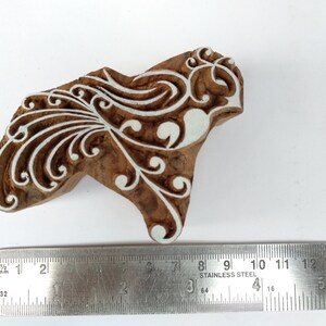 K&ouml;nnte beinhalten: Ein Holzblock-Stempel mit einem wei&szlig;en floralen Design. Der Stempel ist etwa 7,6 cm breit und 5,1 cm hoch.