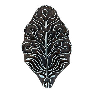 May include: A wooden block printing stamp with a floral design. The stamp is dark brown with a white floral pattern. The design features a central stem with leaves and flowers.