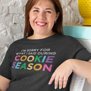 May include: A dark grey t-shirt with the text "I'm sorry for what I said during cookie season" in colorful letters. The letters are in a retro style font.