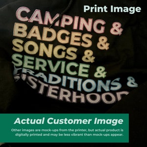 以下が含まれることがあります： 「Camping & Badges & Songs & Service & Traditions & Sisterhood」と虹色の文字が書かれた黒いパーカー。