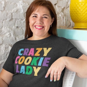 May include: A dark grey t-shirt with the text "CRAZY COOKIE LADY" in rainbow colours.