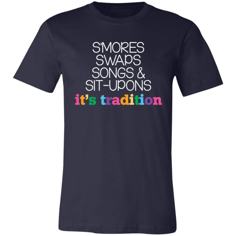 May include: Navy blue t-shirt with white text that reads "S'mores Swaps Songs & Sit-Upons it's tradition". The text is in a rainbow of colors.