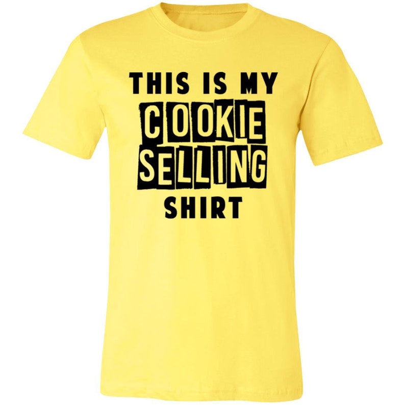 May include: Yellow t-shirt with black text that reads "This is my cookie selling shirt".