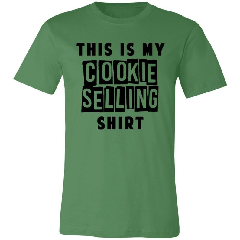 May include: Green t-shirt with black text that reads "This is my cookie selling shirt."