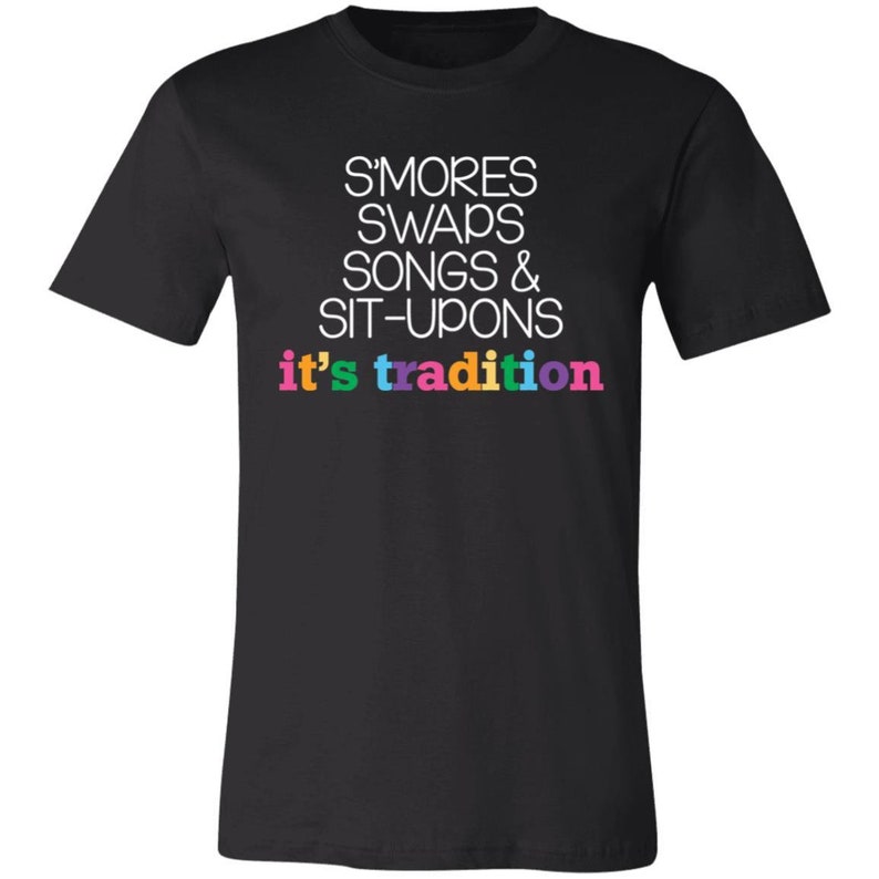 May include: Black t-shirt with white text that reads "S'mores Swaps Songs & Sit-Upons it's tradition". The text "it's tradition" is in rainbow colors.