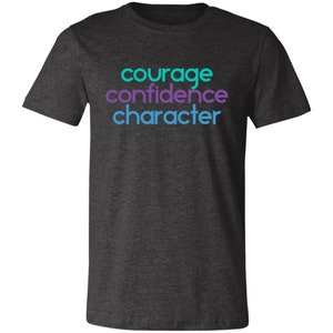 May include: Dark heather grey t-shirt with the words "courage", "confidence", and "character" printed in turquoise and purple.