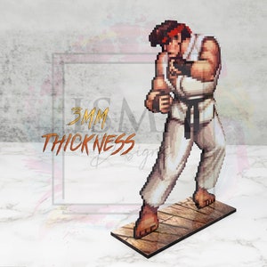 May include: A 3D printed figurine of a video game character, Ryu from Street Fighter, in a fighting pose. The figurine is made of wood and is 3mm thick. The figurine is painted in a pixelated style, similar to the original video game.