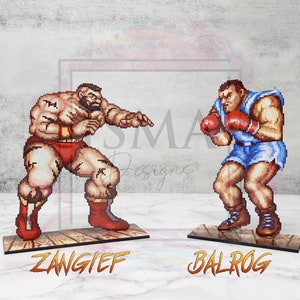 May include: Two pixel art figures of video game characters, ZANGIEF and BALROG, stand on wooden platforms. ZANGIEF is a muscular, red-clad wrestler with a beard, and BALROG is a boxer wearing blue shorts and red boxing gloves.