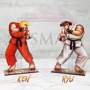 May include: Two pixel art figures of video game characters, Ken and Ryu, from the Street Fighter series. Ken is wearing a red gi with a black belt and Ryu is wearing a white gi with a black belt. Both figures are in a fighting stance.