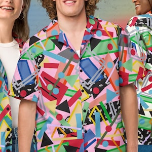 May include: A short-sleeved button-down shirt and a blazer with a colorful geometric pattern. The design features pink, blue, green, and yellow shapes. The shirt has a collar and buttons. The blazer has a lapel and buttons.