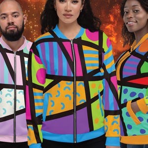 May include: Three colorful bomber jackets with geometric patterns in shades of pink, blue, green, yellow, and black. The jackets have a zipper closure and a ribbed collar.