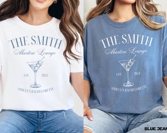 Może przedstawiać: Dwie białe i niebieskie koszulki z grafiką kieliszka do martini i tekstem "The Smith Martini Lounge Est. 2024 Ashley's Bachelorette".