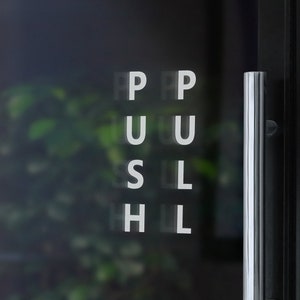 May include: A glass door with a silver handle and the word "PUSH" written in white letters on the glass.