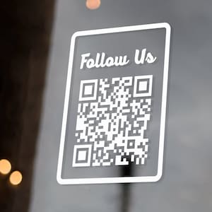 May include: White sticker with a QR code and the text "Follow Us" on a glass door.