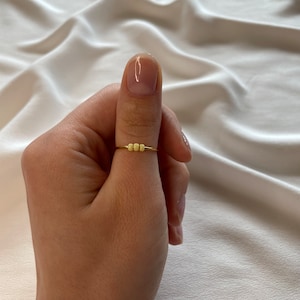 May include: A gold ring with a row of small yellow beads.