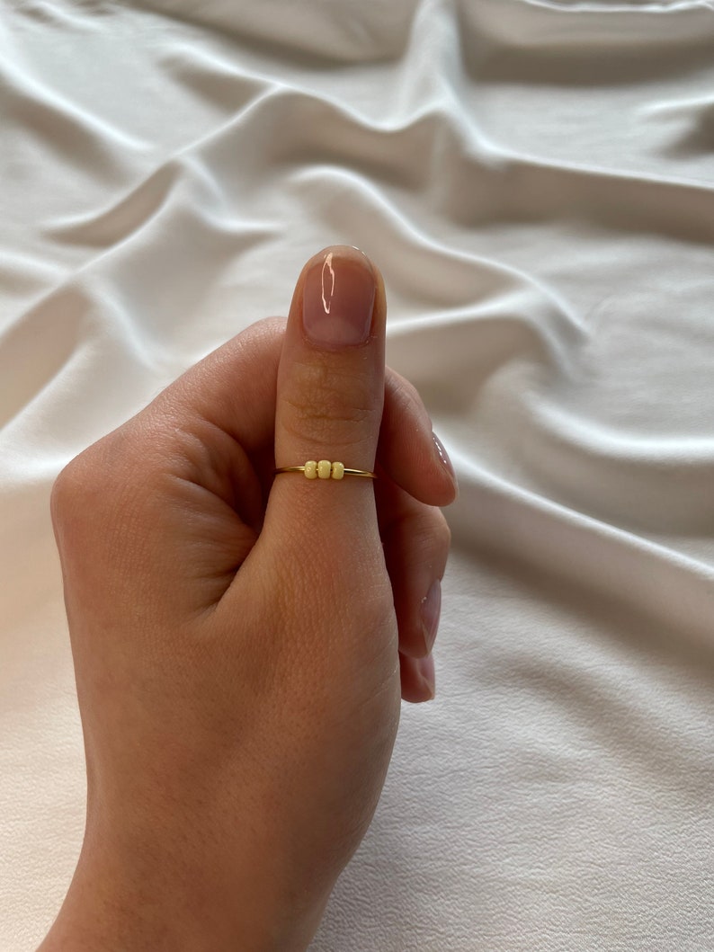 May include: A gold ring with a row of small yellow beads.
