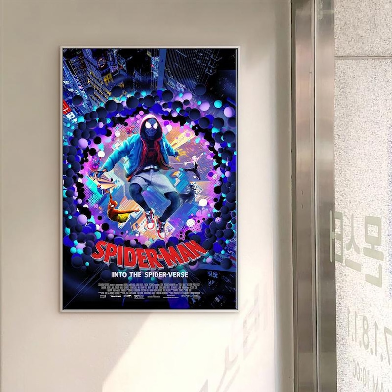 May include: A framed movie poster for "Spider-Man: Into the Spider-Verse." The poster shows Spider-Man in a blue jacket and shorts, set against a colourful background. The film's title, in red, is prominently displayed.