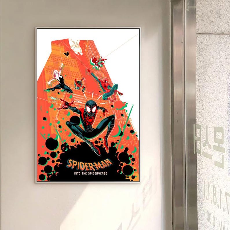 May include: Framed poster with multiple Spider-Man characters in action against an orange and red cityscape backdrop. The poster includes the text "Spider-Man Into the Spiderverse" at the bottom, with various Spidermen swinging and posing.