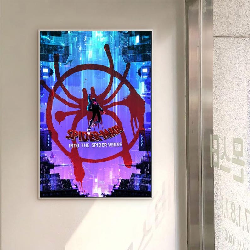 May include: A framed poster for the film "Spider-Man: Into the Spider-Verse." The artwork uses a vivid colour palette, with a red spider-web design over a cityscape. The Spider-Man character is central, with the title text beneath.