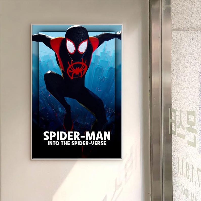 May include: Framed poster of Spider-Man from "Into the Spider-Verse." The character is in a dynamic pose, wearing a black suit with red details and a spider emblem. The background shows a cityscape with the film's title.