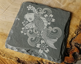May include: A black slate coaster with a white engraved design of a koi fish swimming through cherry blossoms.