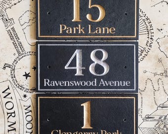May include: Three black slate house number plaques with gold and silver lettering. The top plaque reads "15 Park Lane", the middle plaque reads "48 Ravenswood Avenue", and the bottom plaque reads "1 Glengarry Park".