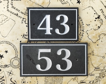 May include: Two black slate house numbers with white lettering. The top number is 43 and the bottom number is 53.