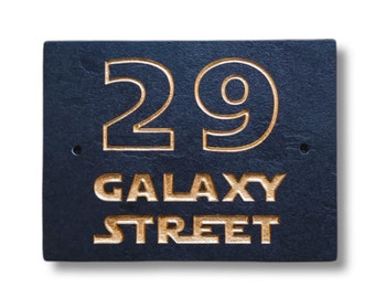 May include: A black slate house number sign with gold lettering. The number 29 is displayed in a large font, followed by the words "Galaxy Street" in a smaller font.