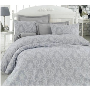 May include: A gray and white patterned duvet cover set with a white pillow and a gray pillow. The duvet cover has a floral design.