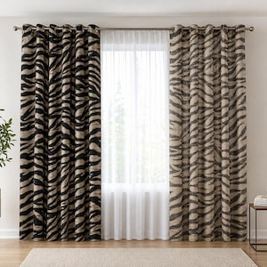 Può includere: Un set di tende a tutta altezza caratterizzato da un audace motivo a strisce zebrate nere e beige, appese a un bastone in metallo argentato. Le tende sono abbinate a un pannello interno bianco trasparente che copre la finestra, creando un effetto a strati.