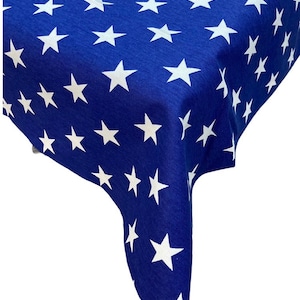 May include: A blue tablecloth with a white star pattern. The tablecloth is rectangular with a drop on each side.