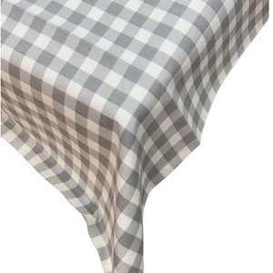 May include: A gray and white checkered tablecloth with a subtle sheen. The tablecloth is folded in a corner, showing the fabric's texture.