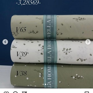 May include: Three rolls of fabric with a floral pattern. The fabric is white, light green, and dark green. The fabric is labeled "Wella Home Poplin" and is 100% cotton.