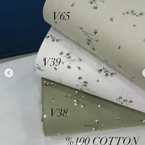 May include: Three fabric swatches with a small white floral pattern. The top swatch is a light beige color, the middle swatch is white, and the bottom swatch is a light green color. The swatches are labeled with the codes V65, V39, and V38. The bottom swatch also has the text %100 COTTON.