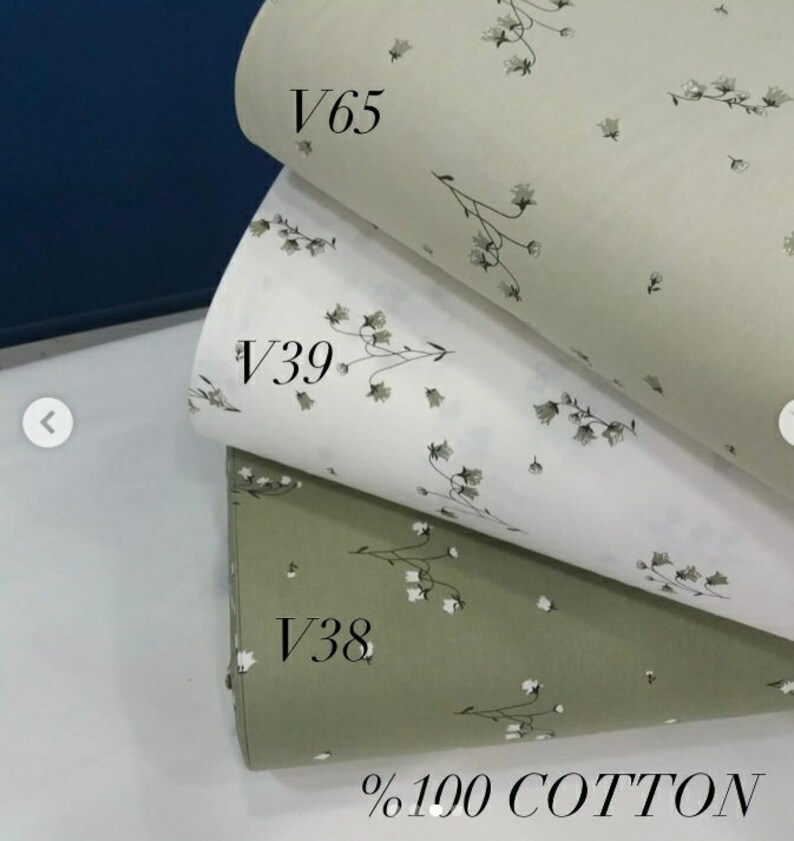 May include: Three fabric swatches with a small white floral pattern. The top swatch is a light beige color, the middle swatch is white, and the bottom swatch is a light green color. The swatches are labeled with the codes V65, V39, and V38. The bottom swatch also has the text %100 COTTON.