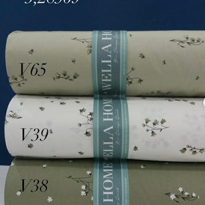 May include: Three rolls of fabric with a floral pattern. The fabric is in shades of green and white. The fabric is labeled with the text "LA HOME ELLA HOME WELLA HOME" and the text "Bir Dinga Bed".