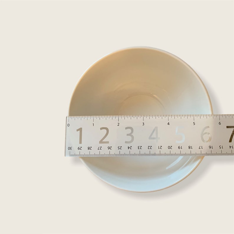 May include: A white ceramic bowl with a diameter of 6 inches. The bowl is sitting on a white surface.