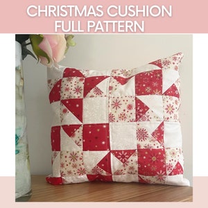 Op de afbeelding: Een rood en wit kerst kussen met een sneeuwvlokkenpatroon. Het kussen is gemaakt van stof en heeft een vierkante vorm. Het kussen ligt op een houten oppervlak.